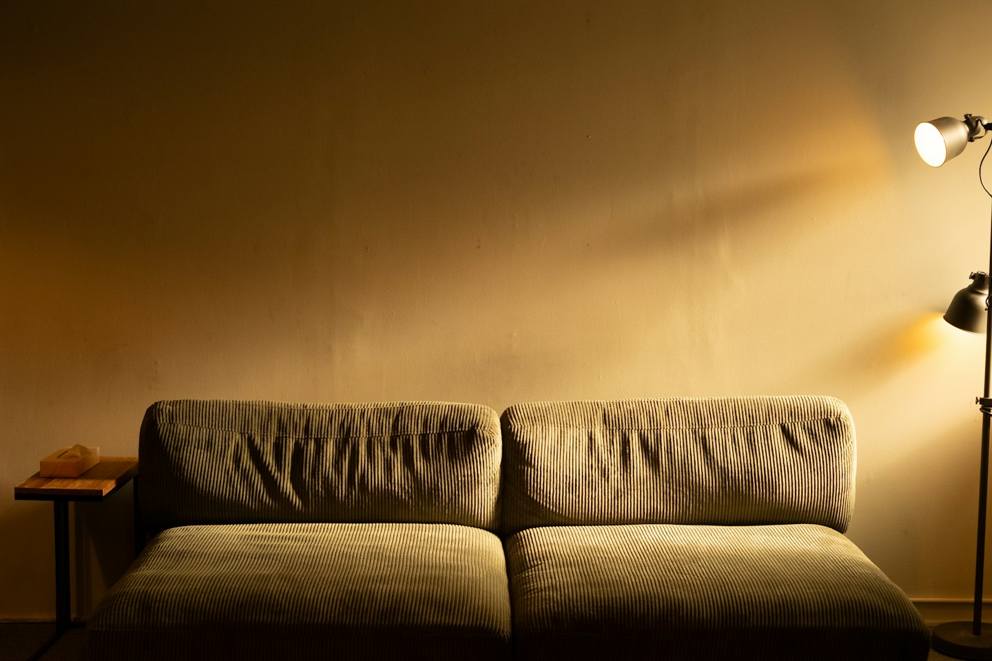 A low sofa beside a standing lamp in warm evening light