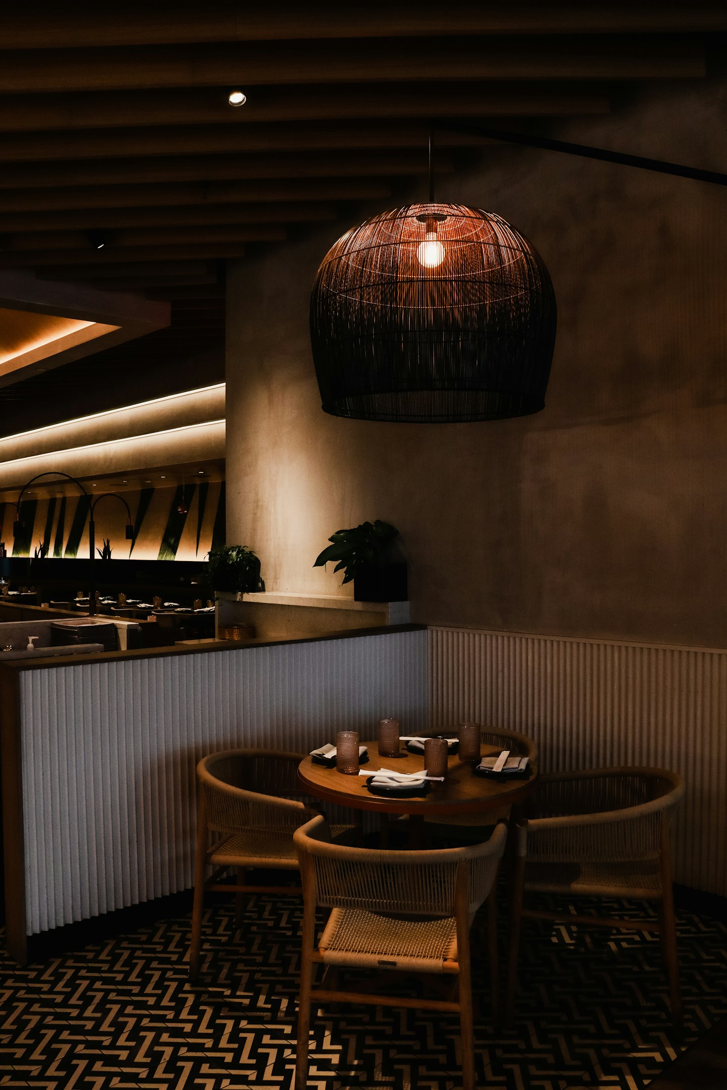 A dimly lit restaurant with plaster walls and rattan lamps